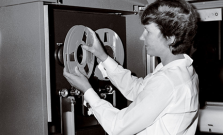 A woman adjusting reels on an old computer