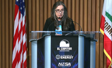 Kim Budil speaks from a podium in the auditorium