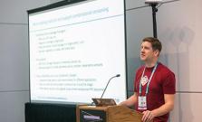 Todd at a lectern next to a presentation screen