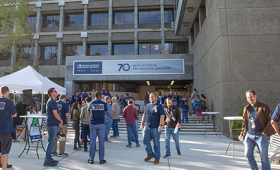 A crowd of people outside an LLNL building adorned with a banner for the laboratory's 70th anniversary